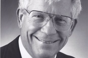 Black and white portrait of Professor George McGill, smiling at camera