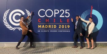 Dr. Benjamin Keisling, Dr. Julian Reyes, and Hannah Baranes, all in formal attire, striking poses in front of wall with dark blue COP25 logo.