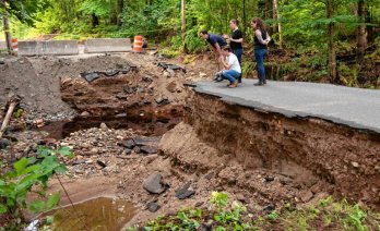 Rep. Jacob R. Olivera, kneeling, Sen. Eric P. Lesser, Conservation Commission Administrator Erica Larner, and Jen Turner, the chair of the select board in Belchertown, look over the damage on July 21 caused by the flooding on East Street in Belchertown on July 18. STAFF PHOTO/CAROL LOLLIS Testing Source: Daily Hampshire Gazette