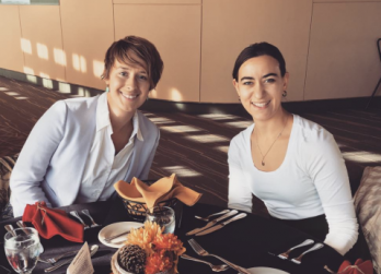 Sarah and Karin seated at a table in a room decorated with warm colors, dining.